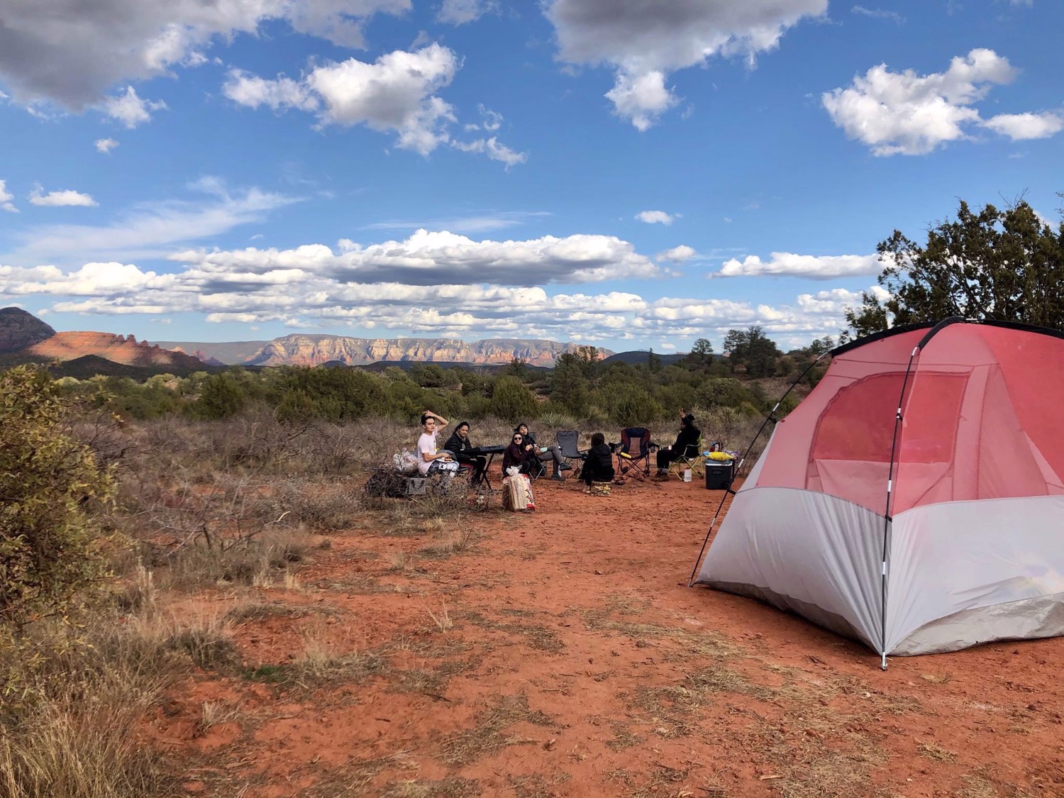A tent and group campsite sit in open desert beneath a bright blue sky.