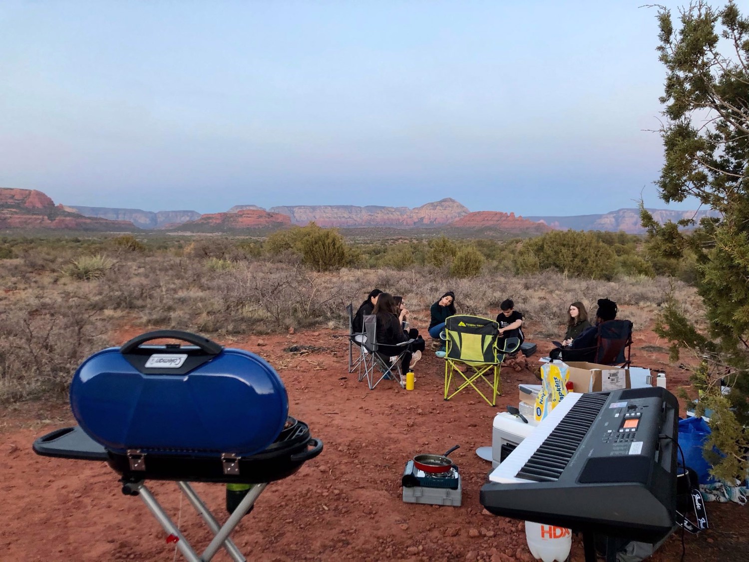 Club members sit together in camp chairs with desert mountains in the distance.