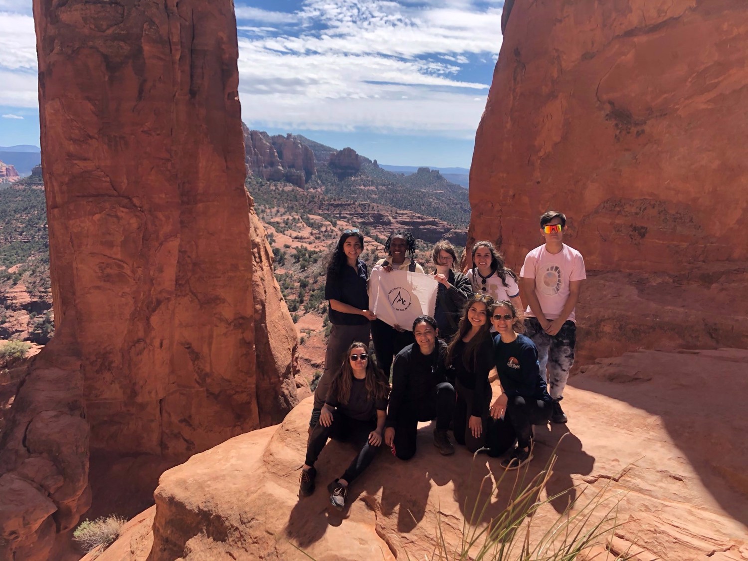 A Mountain Club group poses together between towering red sandstone walls.
