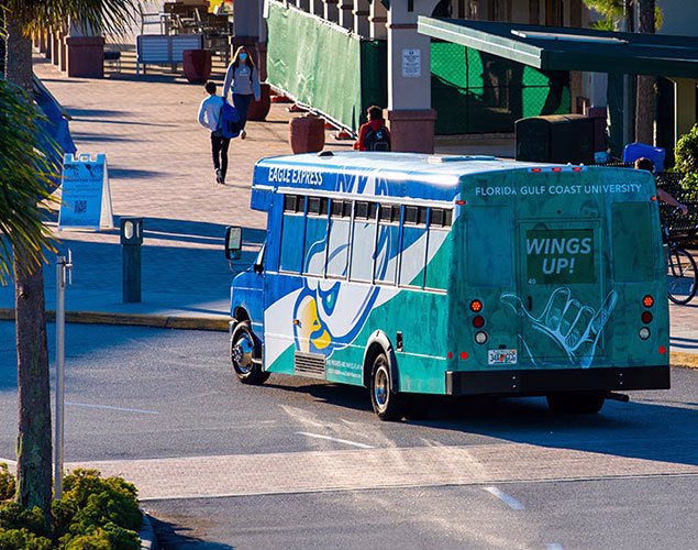 Photo shows FGCU Eagle Express shuttle bus stopping at FGCU's bus loop near Howard Hall